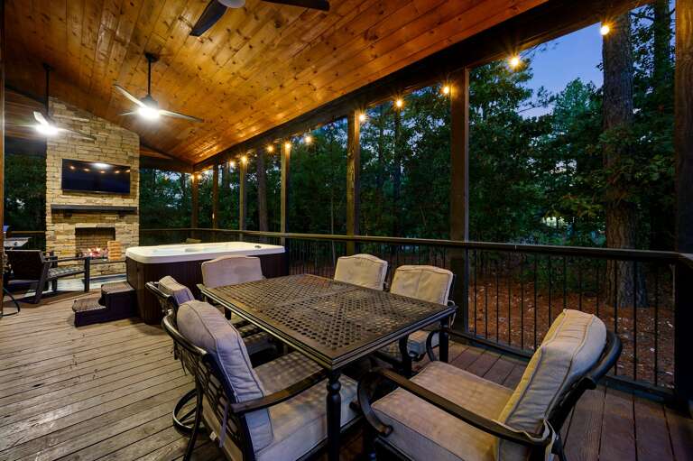 Back patio deck with a dining table, hot tub, fireplace with seating and grill.