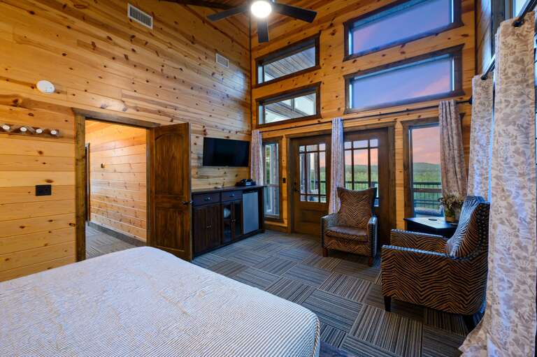 Upstairs bedroom with balcony access, shared bathroom to bunk room and TV.