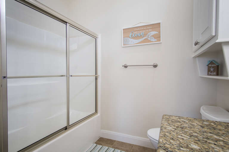Private bathroom with single vanity and bathtub / shower combo.