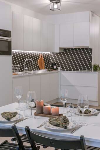 Dining Nook In Vacation Rental With Blue Chairs, Set Table, Black-patterned Backsplash
