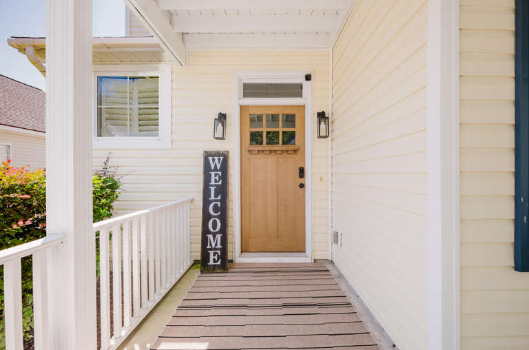 Wooden Walkway Leading To A House Entrance With A Welcome Mat