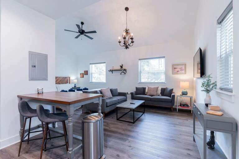 Brightly Lit Vacation Rental Living Room With Sleek Seats And Wooden Table
