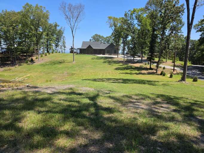 Spacious lawn and charming cabin surrounded by mature trees, with beautiful scenic views.