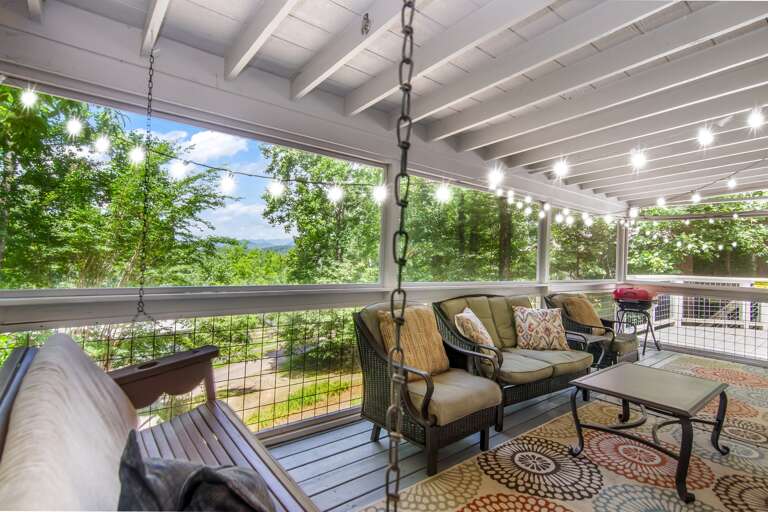 ozy screened-in porch with twinkle lights and forest views