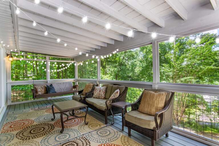 ozy screened-in porch with twinkle lights and forest views