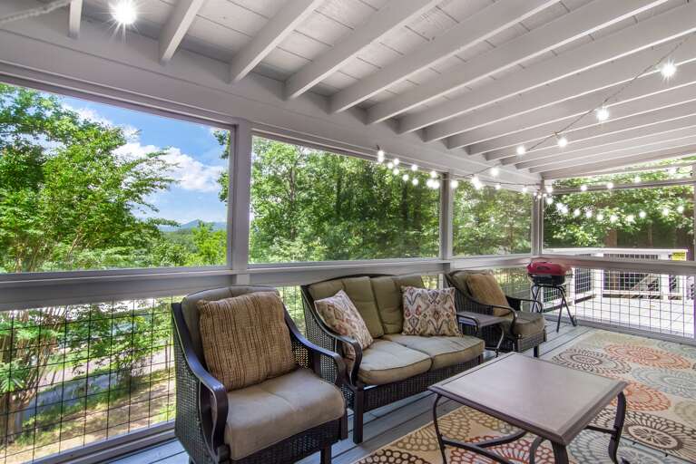ozy screened-in porch with twinkle lights and forest views