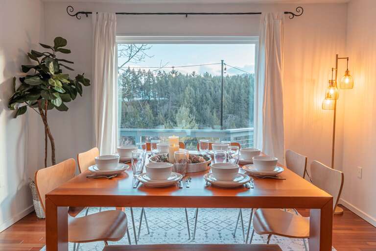 Dining Room With Set Table And Forest View Through Window