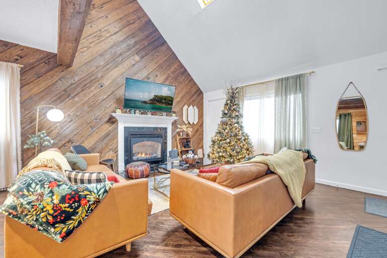 Interior Showing Sofa, Seasonal Tree, And Slanted Ceiling With Wooden Beams