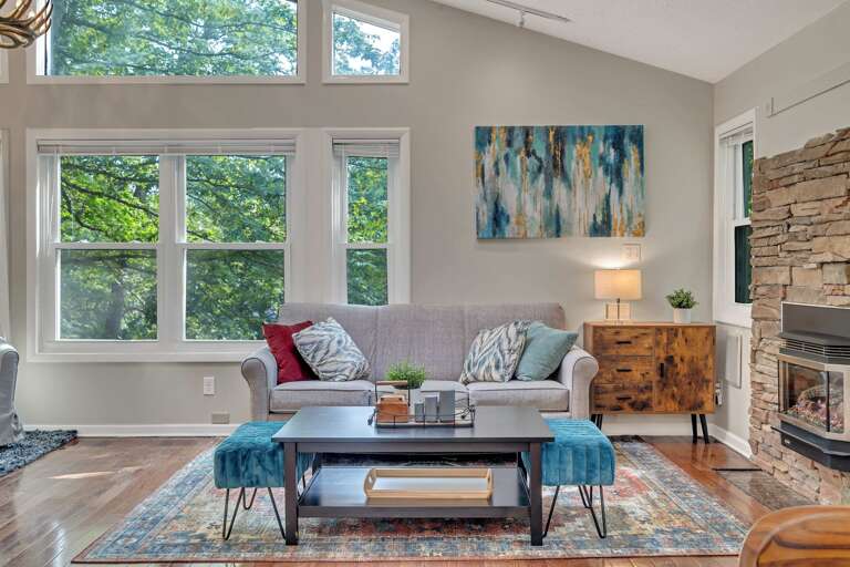 Living Room With Large Windows, Stone Fireplace, And Teal Accents
