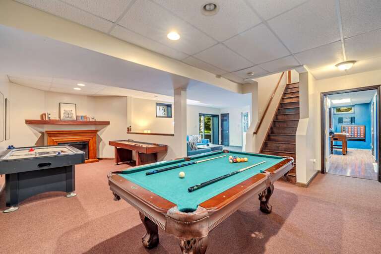 Spacious Recreation Room With Pool Table And Staircase In Vacation Rental