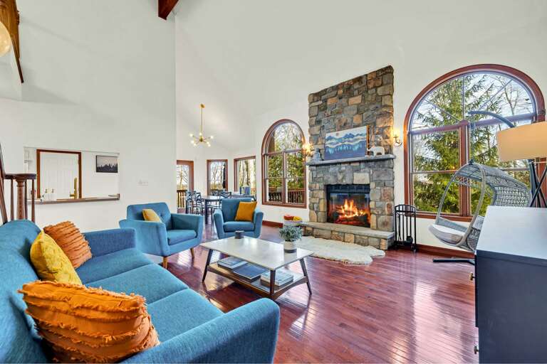 Spacious Living Space With Stone Fireplace, Arched Windows, And Blue Sofas
