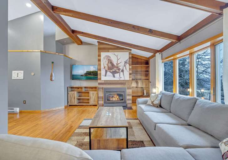 Living Room With Fireplace, Wooden Beams, And Large Windows
