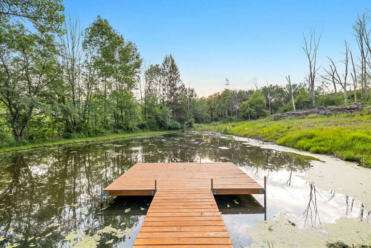 Wooden Dock On Tranquil Pond Surrounded By Lush Trees
