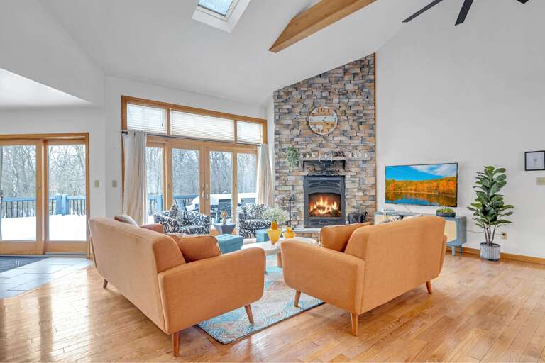 Bright Room With Beige Chairs, Stone Fireplace, Large Windows