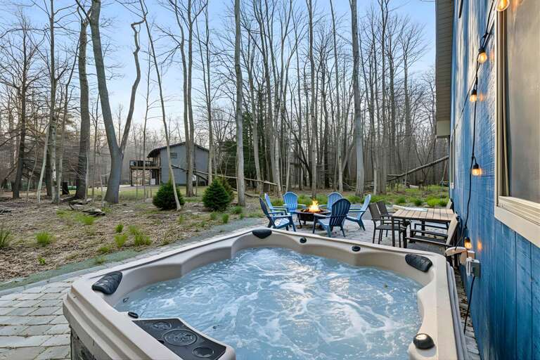 Vacation Rentals Bubbling Outdoor Hot Tub Beside Blue Building, Under Bare Tree Branches