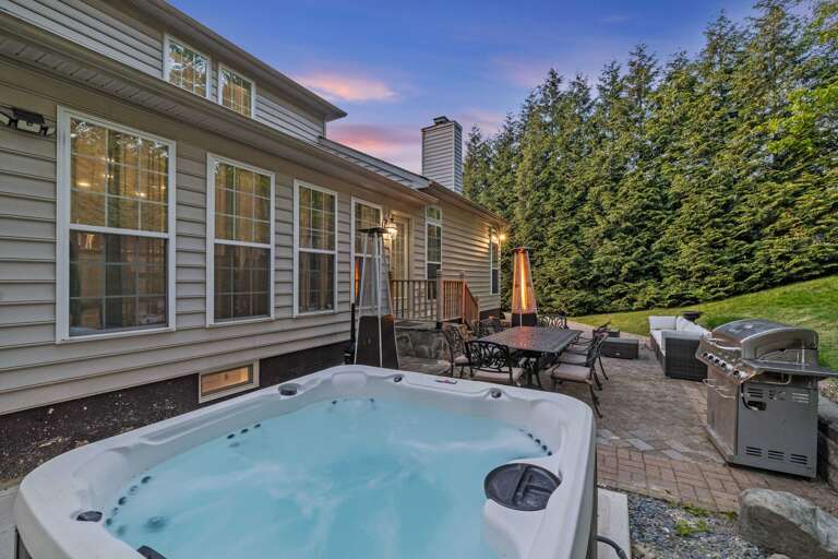 Patio With Bubbling Hot Tub, Grill, And Dining Set Amidst Greenery
