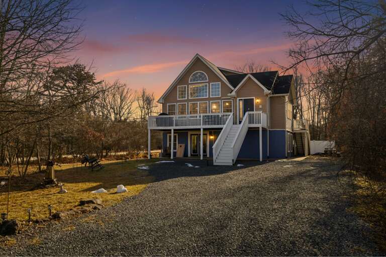 Large Blue House Bathed In Sunset Hues, Surrounded By Bare Trees