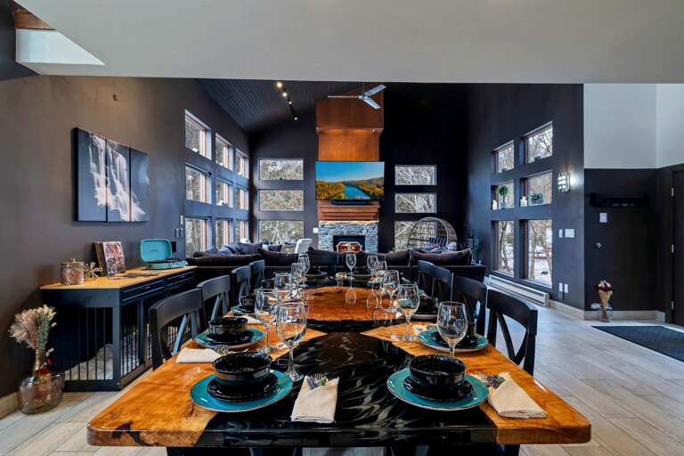 Dining Table With Dishes, Large Windows, Artwork On Dark Walls