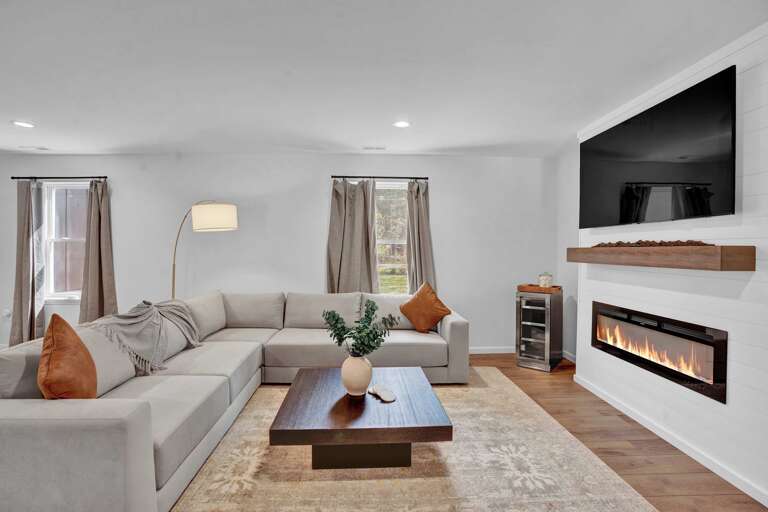 Living Room With Large Sofa, Wall-mounted TV, And Electric Fireplace