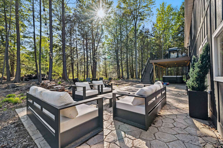 Sunlit Stone Patio With Plush Seating Amidst Towering Trees