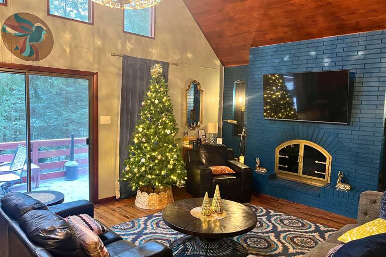 Brightly Lit Living Space With A Christmas Tree And Fireplace, Opening To A Deck