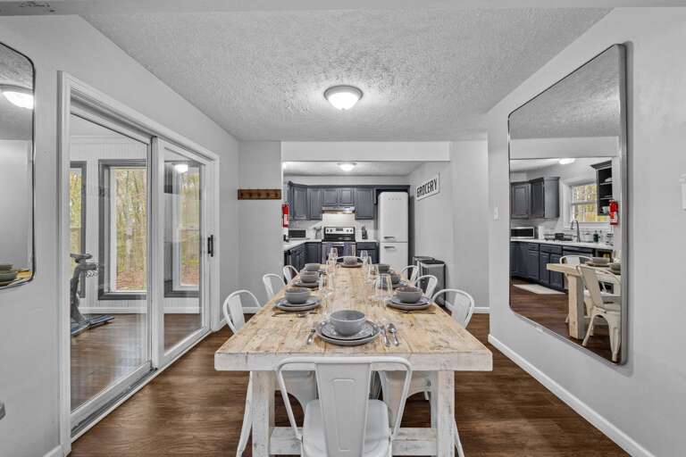 Bright Dining Space Leading To A Kitchen, Large Table Set For Dining, Sliding Doors On Left