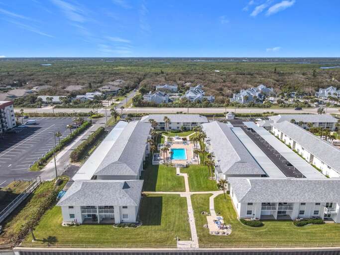 Aerial view of the serene coastal property, featuring lush landscaping and oceanfront access.