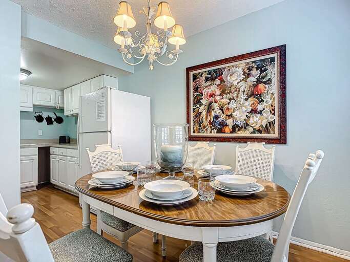 Gather around the beautifully set dining table, featuring a charming chandelier and vibrant artwork.