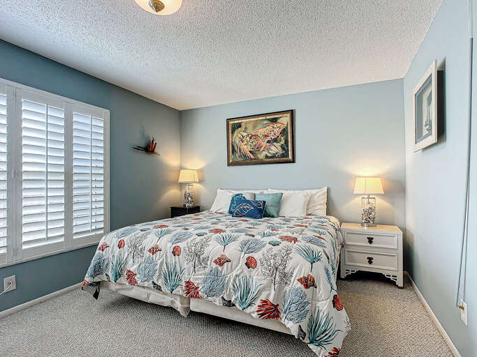 A tranquil bedroom with coastal decor, soft lighting, and a comfortable bed.