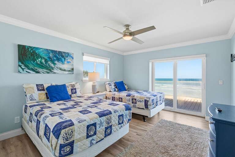 This bright bedroom features two beds, coastal décor, and direct access to a beachfront balcony.