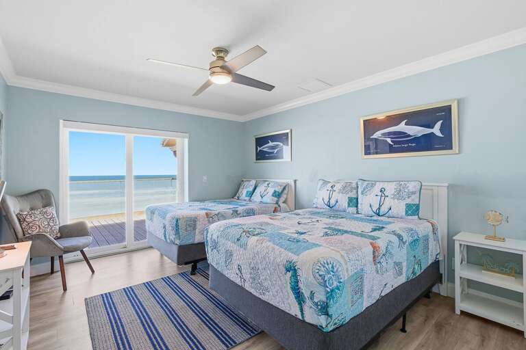 This bright bedroom features two beds, coastal décor, and direct access to a beachfront balcony.