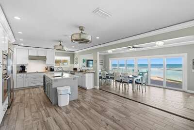 Bright open-concept kitchen and dining area with modern finishes, large island, and floor-to-ceiling