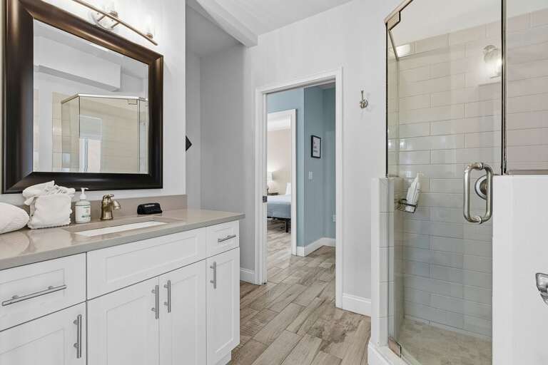 Enjoy this stylish bathroom featuring a walk-in glass shower, spacious vanity, and clean coastal