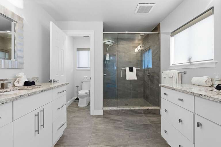 Indulge in this spacious bathroom with dual vanities and a large walk-in shower. Perfect for your beach stay, enjoy a relaxing, spa-like experience after a day in the sun and surf.