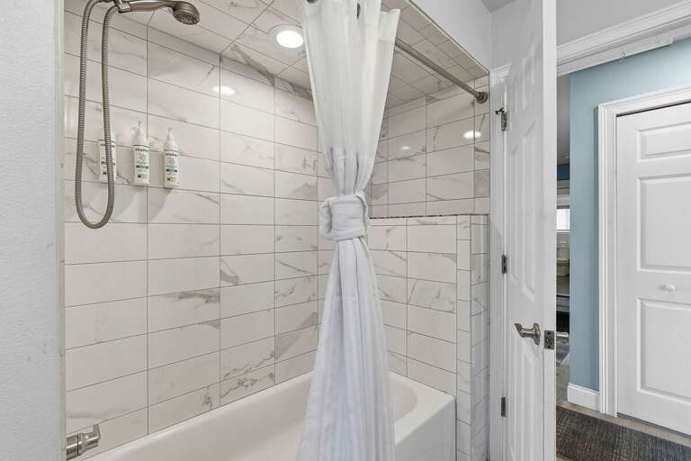 Unwind after a day at the beach in this bright bathroom featuring a tub and shower combo with modern tile. Ideal for your beach stay, offering a clean, relaxing space to refresh and recharge.