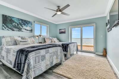 Bright coastal bedroom featuring two comfy beds, serene sea-inspired décor, and private balcony access—perfect for waking up to ocean breezes and enjoying a relaxing beach stay.