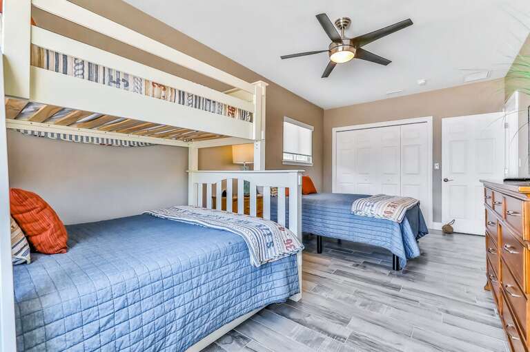A bright and beach-inspired bunk room featuring multiple beds, cozy linens, and plenty of space—perfect for families enjoying a relaxing seaside stay.