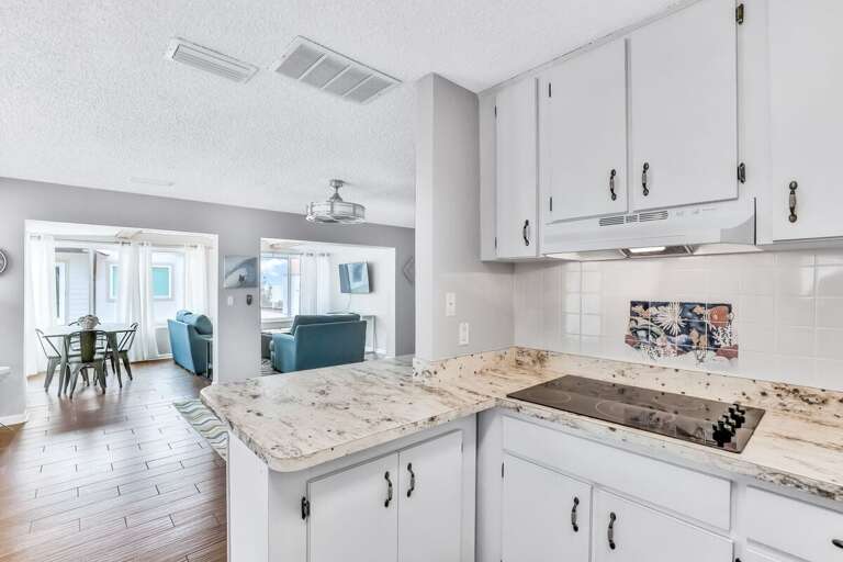 Charming beach stay kitchen with vintage touches and spacious counters flows into sunlit dining and living areas—perfect for prepping meals before heading out for oceanfront fun.