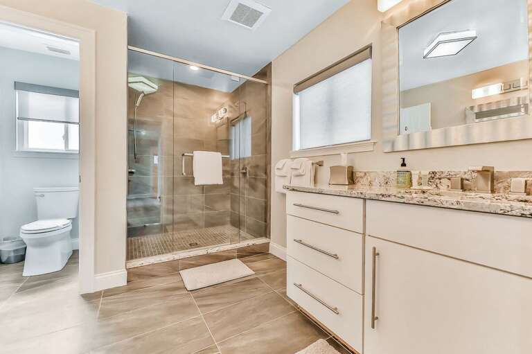 A luxurious spa-inspired bathroom featuring a spacious walk-in shower, double vanity, and modern finishes—perfect for unwinding after a fun-filled day at the beach during your coastal stay.