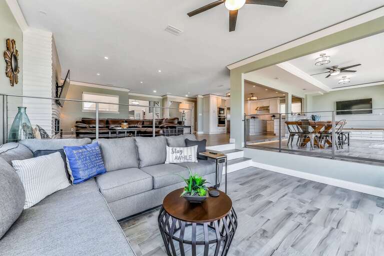 Relax in this airy coastal living space featuring plush seating, modern décor, and open flow to the kitchen and dining areas—perfect for unwinding after a sun-soaked beach stay.