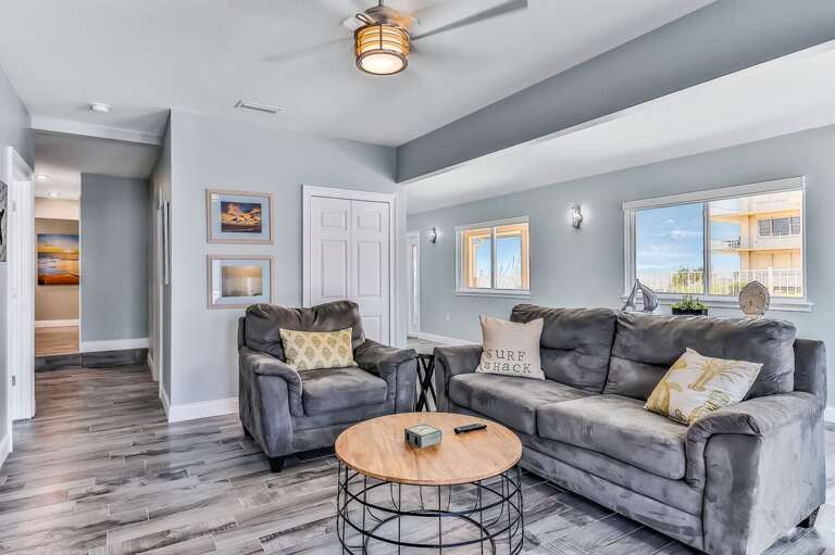Relax in this airy beach-inspired living room featuring plush seating, coastal décor, and plenty of natural light—perfect for unwinding after a sun-filled beach stay.