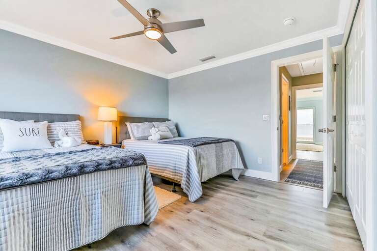 Relax in this bright coastal guest room featuring two comfy beds, soft beach-inspired décor, and plenty of space to unwind after a sun-filled beach stay. Perfect for families or friends.