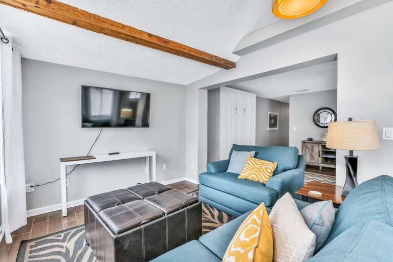 Relax in this cozy coastal living room featuring plush seating, beach-inspired décor, and a flat-screen TV—perfect for unwinding after a sun-soaked day by the shore.