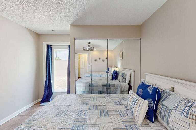 Relax in this beach-themed bedroom featuring soft coastal tones, mirrored closets, and private patio access—perfect for unwinding after a sun-soaked beach stay.