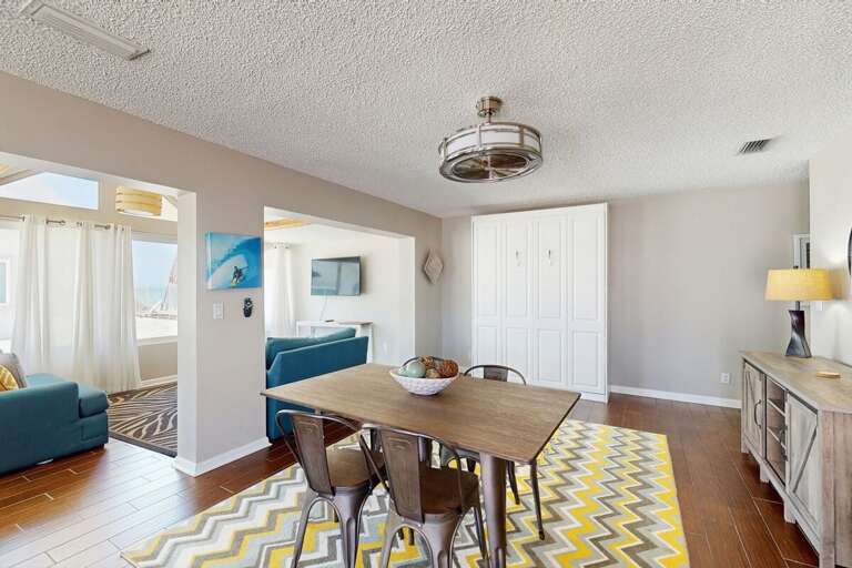 A sunny dining space perfect for relaxing after a day at the beach. Enjoy coastal décor, warm natural light, and easy flow to the living areas—ideal for shared meals during your beach stay.