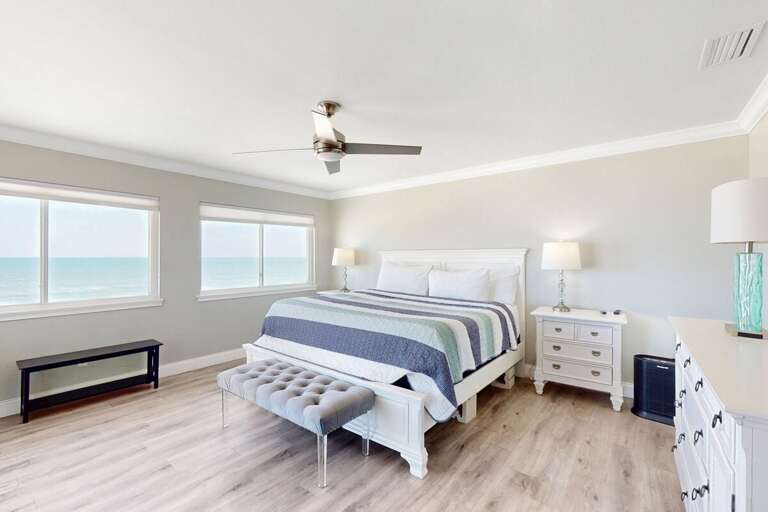 Wake up to endless ocean views in this bright, coastal primary suite. Cozy bedding and serene décor create the perfect beach stay escape just steps from the shoreline.