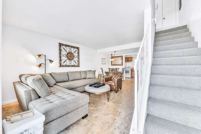 Bright, open living space with comfy seating and dining area—perfect for relaxing after a fun beach stay. Enjoy a welcoming layout just steps from the shoreline.