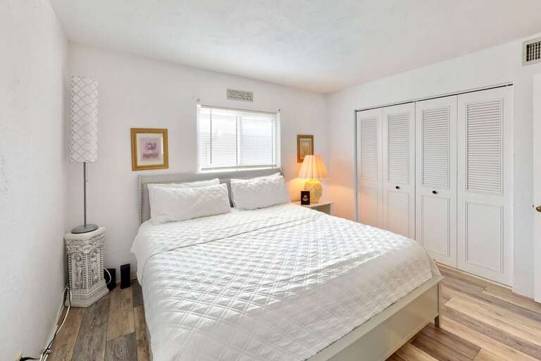Relax in this sunlit beachside bedroom featuring a plush king bed, coastal décor, and soothing tones—perfect for unwinding after a day of oceanfront adventures during your beach stay.