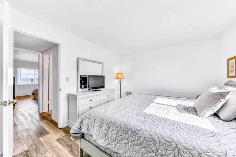 Relax in this sunlit bedroom featuring a cozy bed and modern furnishings. A perfect spot to unwind after a fun-filled beach stay, with calming coastal vibes throughout.