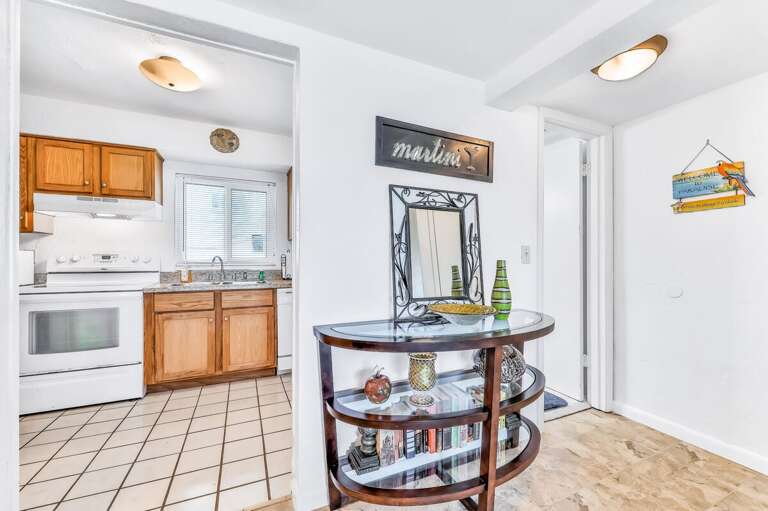 A welcoming entryway leads into a bright kitchen, perfect for easy meals during your beach stay. Coastal décor and natural light create a warm, inviting start to your seaside getaway.